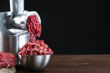 Close-up shot of a meat grinder from a short meat is minced into a small iron bowl