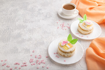 Decorated cake with milk and coconut cream with cup of coffee on a gray concrete background. Side view, copy space.