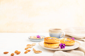 Small cheesecakes with jam and almonds with cup of coffee on a white concrete background. Side view, copy space.