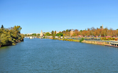 Obraz premium Panoramic view of the Guadalquivir river with the Gold Tower (Torre del Oro), Giralda and St Telmo Palace (Palacio de San Telmo). Seville, Andalusia, Spain