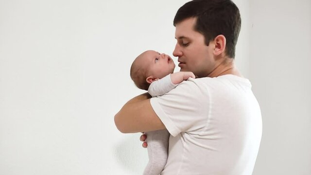Happy father cuddling, smiling and kissing his newborn child. Happy parenting, family moments.
