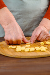 Hands of an elderly woman work with pieces of dest, making blanks for dumplings