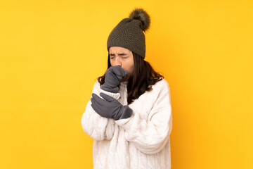 Obraz premium Young woman with winter hat over isolated yellow background is suffering with cough and feeling bad
