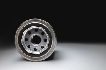 Black new oil filter in contrasting light on a black and white background. Wide angle