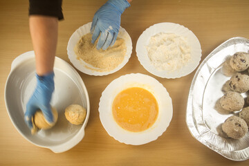 hands of a chef who prepares Sicilian arancini breaded with primary ingredients