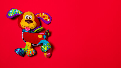 Red orange doggy toy on a red background with copy space for text. Soft plush toy for baby dog banner for toy store.