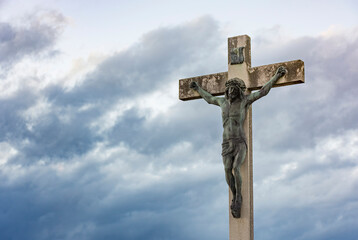 Jesus Christ on the cross against dramatic cloudy sky, at sunset. Crucifixion, religion and spirituality