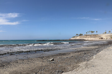 Waves crashing over the black sand and rocks on a beach in Tenerife
