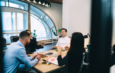 Group of colleagues discussing business project in workspace