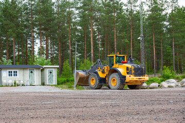 yellow wheel loader bulldozer with huge bucket in the forest road building scene standing in granit rubble