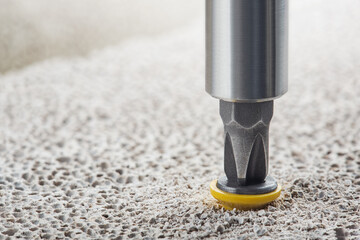 screwdriver screw and dowel in a concrete wall background