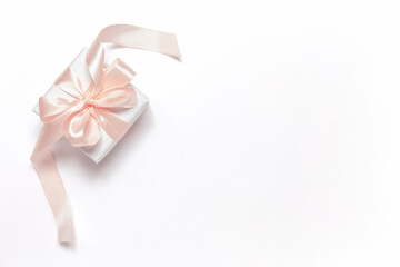 A white gift box tied with a pink ribbon for Valentine's Day, Birthday, Mother's Day or International Women's Day. Festive background