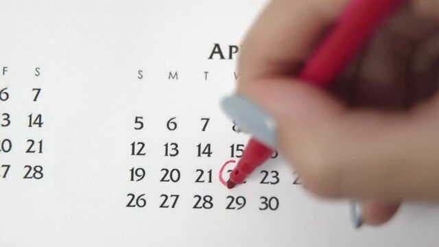 Female hand circle day in calendar date with a red marker. Business Basics Wall Calendar Planner and Organizer. APRIL 22th