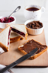 Sandwich with chocolate butter and cherry jam on wooden background. Breakfast with coffee