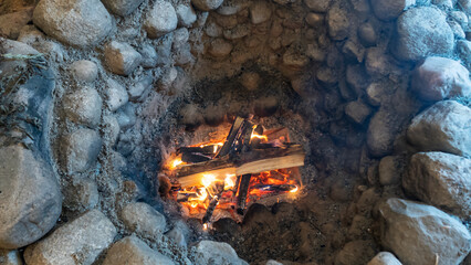 Top view of old stone hearth with burning smoking firewood. Household concept. Space for text.