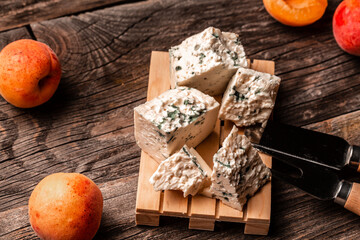 A piece of blue cheese on a wooden board with fresh juicy peach. Food recipe background. Close up