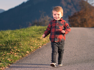 Kleiner zweijähriger Junge läuft lachend einen Weg entlang