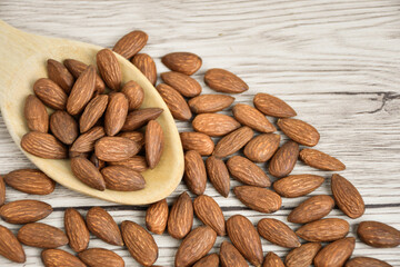 almond nut on wood spoon placed on wood table.