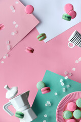 Levitation and balance composition. Flying macaroons, ceramic coffee maker and hand with espresso coffee cup. Geometric layered paper background in pastel colors, pink, cream and mint green.