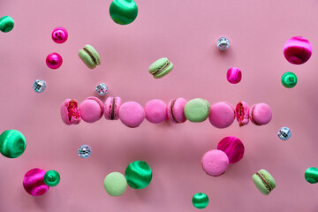 Levitation of macaroons, creative food concept. Bold vibrant pink, mint green and magenta colors. Flying yummy macaroons, mirror disco balls and decorative metallic balls on pink background.