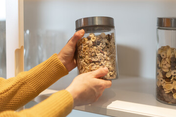 Woman pulls out a glass jar from the shelf