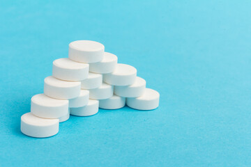 Heap of pills on blue background. Medicine, pharmacy and health concept.