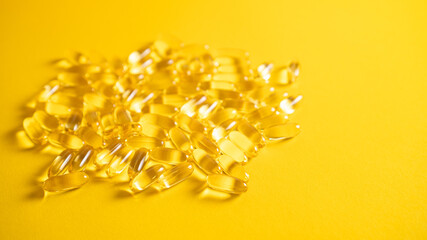 Fish oil capsules with omega 3 on yellow background. Health care concept. Pile of capsules Omega 3...