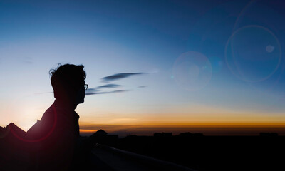 silhouette of person standing on top of building during daytime, sunset.