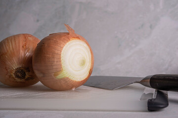 Onions being Sliced on White Cutting Board With Chef's Knif and Wood Stand