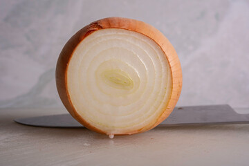 Onions being Sliced on White Cutting Board With Chef's Knif and Wood Stand