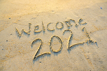 Fototapeta premium Welcome year 2021 inscription written on the sandy beach. Welcoming new year concept.