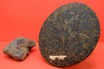 Puer tea from China. Blurred image of red claystone from the mountains where tea grows. Red background. Puerh quality tea concept. Copy space. Mockup.
