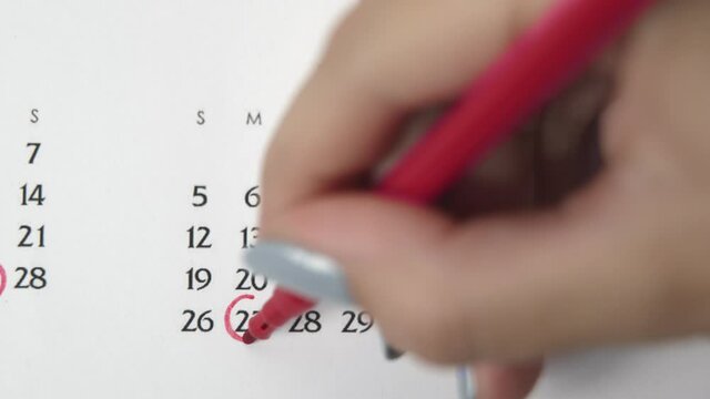 Female hand circle day in calendar date with a red marker. Business Basics Wall Calendar Planner and Organizer. APRIL 27th