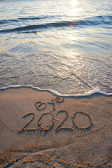 Goodbye 2020 inscription written on the sandy beach. New year conceptual.