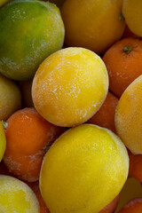 vertical image frozen in ice and snowflakes ripe yellow and green lemons close-up, selective focus