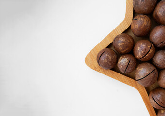 macadamia nuts with slits for opening in a star-shaped bamboo plate, selective focus