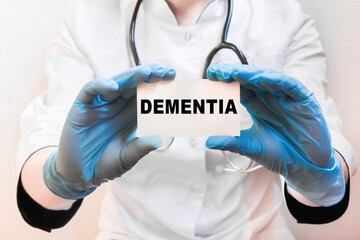 The doctor's blue - gloved hands show the word DEMENTIA - . a gloved hand on a white background. Medical concept. the medicine