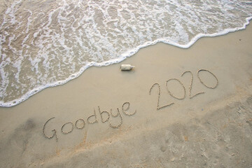 Goodbye 2020 inscription written on the sandy beach. New year conceptual.