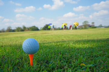 Golf ball on tee in the evening golf course with sunshine background.