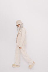 Urban street style Girl in white studio. Details of everyday look. Casual beige outfit and accessories. Bucket hat. Trendy Minimalist fashion