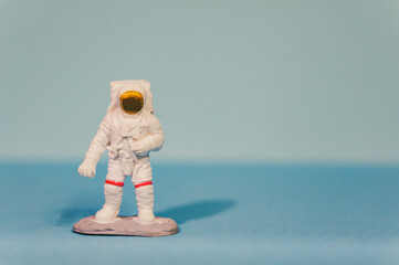 A closeup shot of an astronaut toy with a white spacesuit isolated on a light blue background
