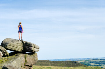Woman standing on a rock boulders at Stanage in the Peak District, Derbyshire, England