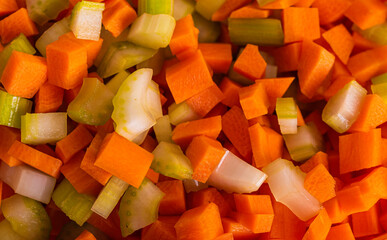 Carrots, Onions and Celery being Sliced on White Cutting Board With Chef's Knife and Wood Stand in a Bowl