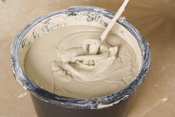 the master mixes the plaster in a bucket. Flat house renovation, master mixed the mortar in a plastic bucket with mixer