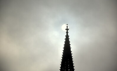 Turm des Freiburger Münsters vor der wolkenbedeckten Sonne
