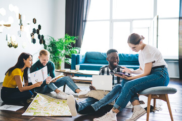 Happy diverse coworkers discussing plans in team sitting in living room