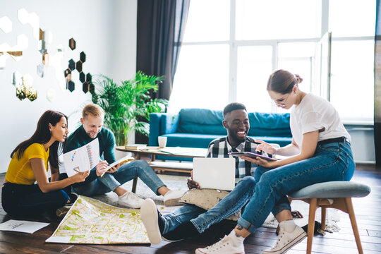 Happy diverse coworkers discussing plans in team sitting in living room