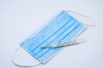 Thermometer and face mask. Medical mask and thermometer on white background.