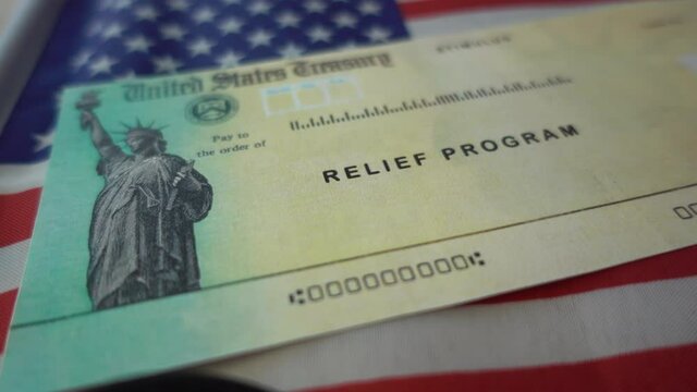 Blurring Stimulus check  relief program on Flag of USA, close up view. 