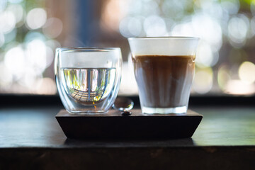 Espresso shot over cold fresh milk create gradient layer called Dirty coffee serve with warm water